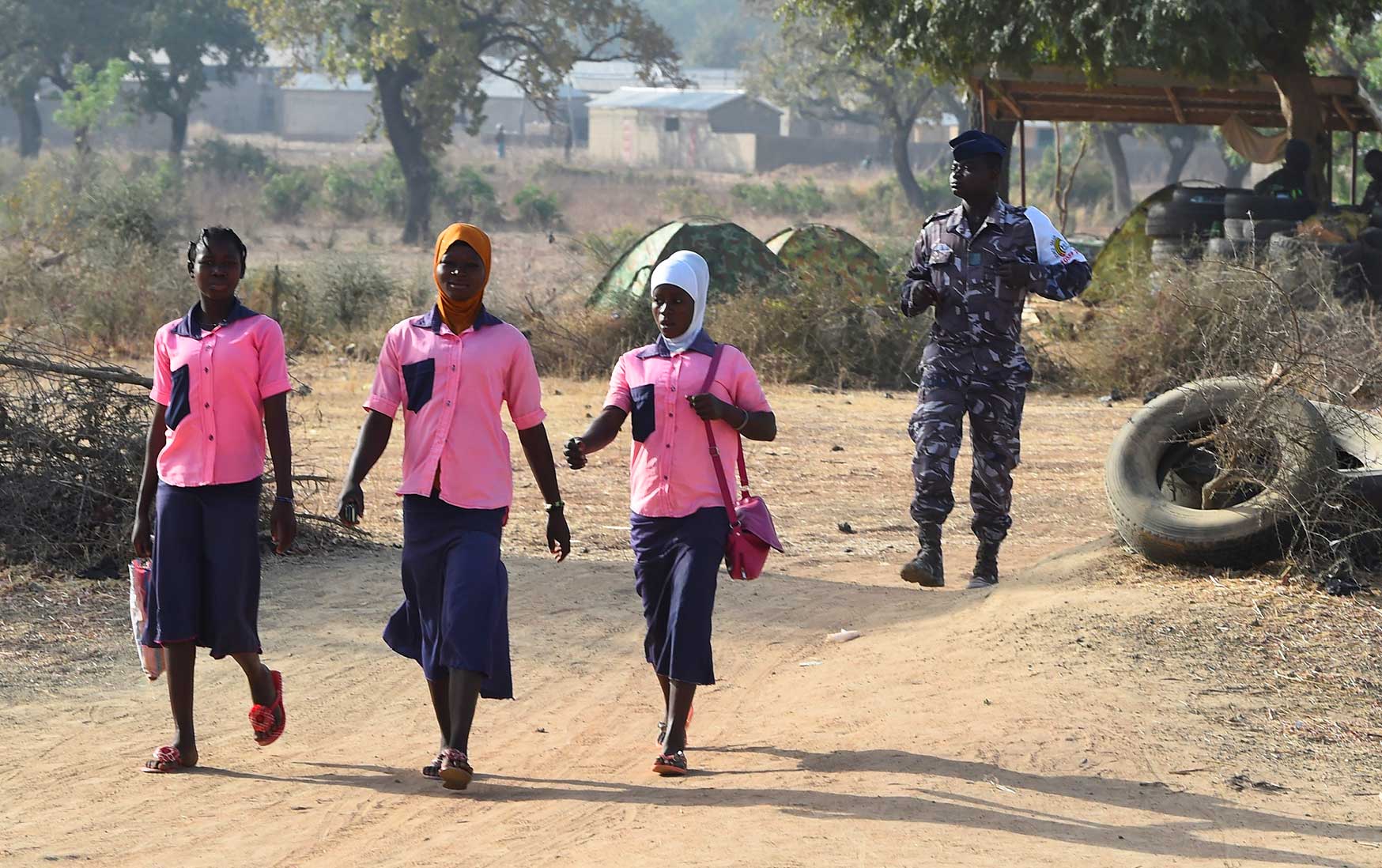 A policeman walks behind school girls